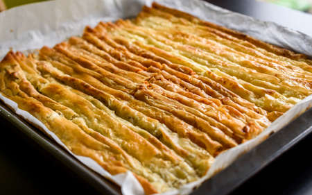 Baked homemade traditional Balkan, Bosnian, Greek, Turkish,Â  Serbian dish burek. Delicious homemade pastryÂ ready to eat. Domestic pastries on backing tray with bake paper. Cheese or meat pie.の写真素材