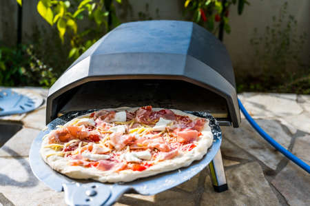 Making homemade pizza in portable high temperature pizza oven.Â Checking the stone temperature with special IR thermometer. Special gas fueledÂ pizza oven for picnic or party.の写真素材