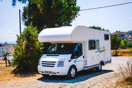 Motorhome RV parked under a tree, Crete, Greece. Travelers with camperÂ van are resting on an...