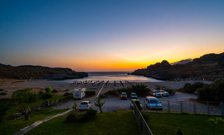 Amazing Skinaria sandy beach in the sunset or dusk with parked cars. Evening night view of beautiful Skinaria beach with cars and motorhome on parking place with sunset - Plakias, Crete, Greece.の写真素材