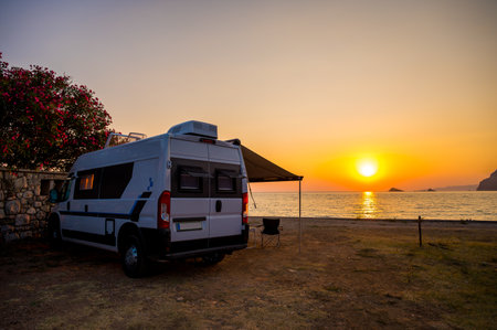 Campervan is parked on the beach at sunset. Campervan is parked on the beach next to the sea - wild camping in Croatia, Montenegro, Albania or Greece. Summer road trip.の写真素材