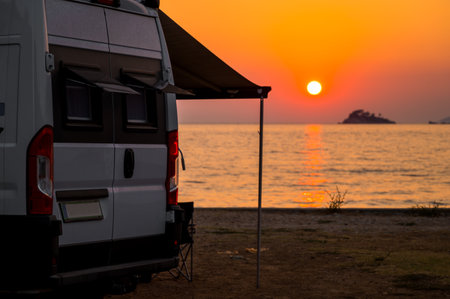 Campervan is parked on the beach at sunset. Campervan is parked on the beach next to the sea - wild camping in Croatia, Montenegro, Albania or Greece. Summer road trip.の写真素材