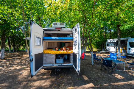 Family waking up in a campervan in the camping campsite. Motorhome with bunk beds is parked on the campsite under the trees in Meteora, Greece. Summer road trip.の写真素材