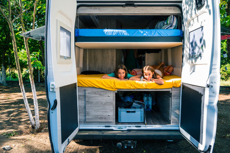 Family waking up in a campervan in the camping campsite. Motorhome with bunk beds is parked on the campsite under the trees in Croatia, Montenegro, Albania or Greece. Summer road trip.の写真素材