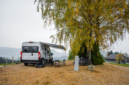 Campervan or motorhome parked in the countryside nature. Woman is drinking coffee in front of camper van motor home RV, parked under the trees when exploring the countryside nature of Slovenia, Europeの写真素材