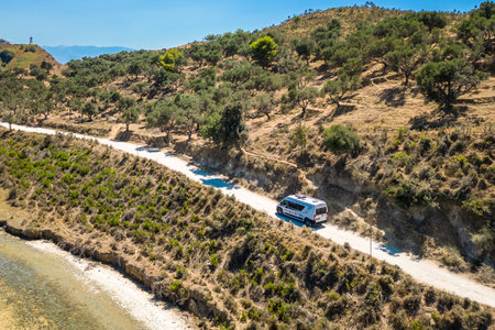 Camper van, RV or motor home is driving on gravel road fromÂ Zvernec beach or Dalan beach near Vlore, Albania. Off Road driving a camper motorhome is exploring wild nature.の写真素材