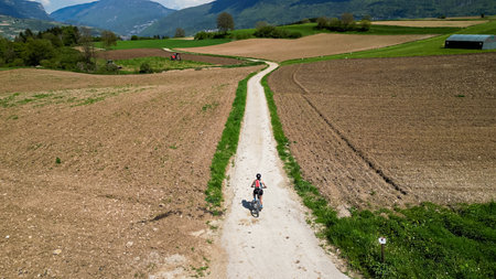 Woman on a bicycle trip in nature with mountain bikes. Active female on biking vacation in Italy near Lake Garda is exploring gravel roads through fields and meadows.の写真素材