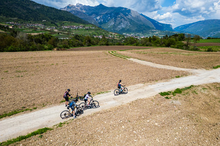 Family on a bicycle trip in nature with mountain bikes. Active family on biking vacation in Italy near Lake Garda is exploring gravel roads through fields and meadows.の写真素材