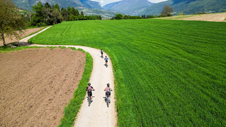 Family on a bicycle trip in nature with mountain bikes. Active family on biking vacation in Italy near Lake Garda is exploring gravel roads through fields and meadows.の写真素材