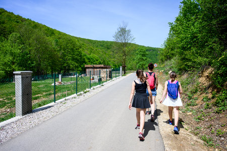 Family hiking or walking on a road to visit the famous Strbacki buk waterfall in Bosnia. Hiking in nature wearing sports clothes.の写真素材