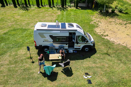 Family camping with a campervan in a campsite in Bosnia near Una River. Family relaxing with camper van, chairs and table on vacation.の写真素材