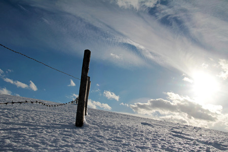 Barbed wire fence with fence post in the winter landscape. An icy winter landscape with fence postsの写真素材