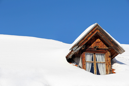 A lot of snow on a house roof. A snowy house roof with roof windowの写真素材