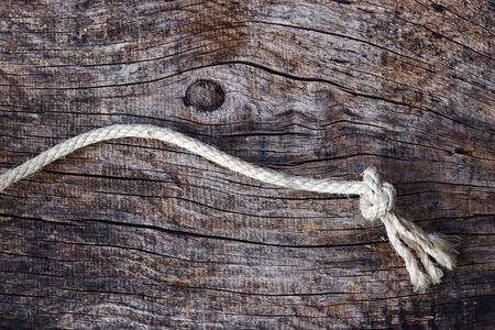 Knotted rope on a wooden base. A rope with a knot on a wooden baseの写真素材