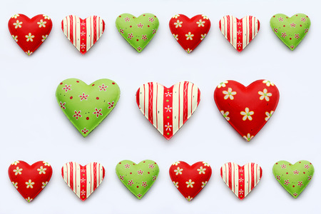 Many colorful hearts on a white background. Red-green hearts made of metal