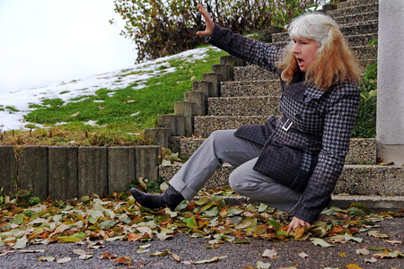 A woman slipped on wet leaves and fur. Wet leaves are dangerousの写真素材