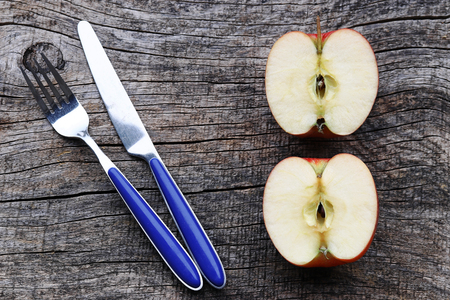 Two half apples and fork on an old wooden tableの写真素材