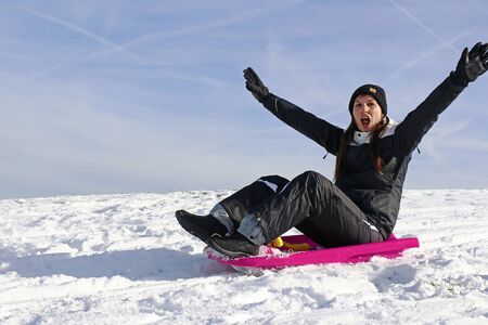 A young woman has fun sledging in winterの写真素材
