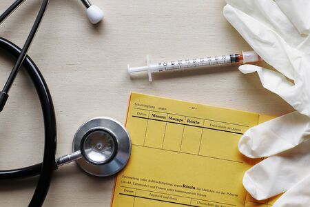 Vaccinations against measles, mumps and rubella with vaccination card and syringe