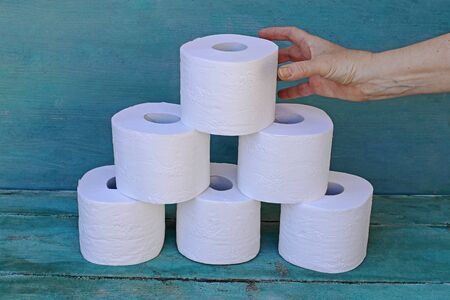 A woman takes a roll of toilet paper from a stack