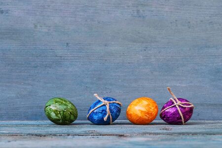 Four colorful Easter eggs on a blue wooden background