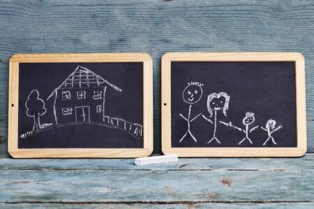 Two blackboards with drawings of a family and a houseの写真素材