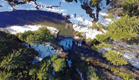 Aerial drone shot of river with waterfall in winter in bavaria