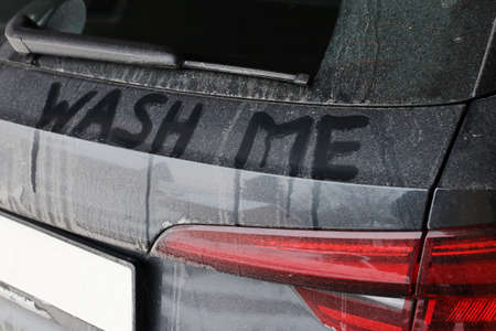 A dirty black car says wash meの写真素材