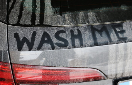 A dirty black car says wash meの写真素材