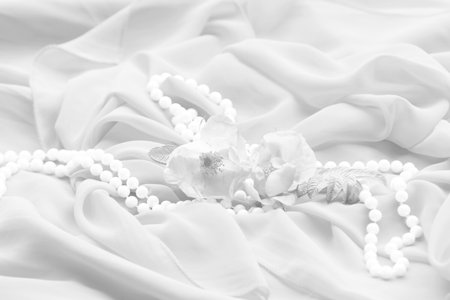 Close-up of fabric with a rose and pearl necklace in whiteの写真素材
