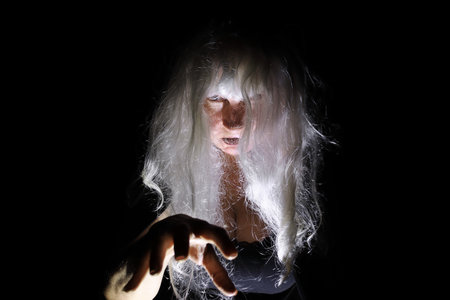 A creepy white-haired old woman in the light and shadows of the night