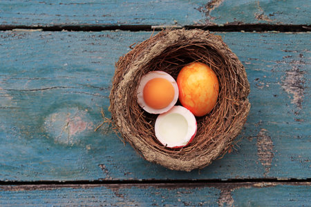 An Easter nest with colorful hard-boiled eggs on a wooden baseの写真素材
