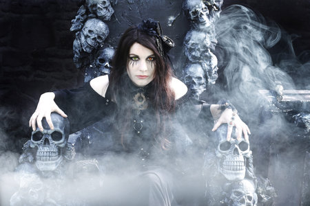 Fantasy photo with an evil witch on a throne with skulls and fog