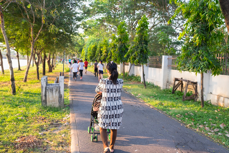 couple of mother with baby in stroller in park in eveningの写真素材