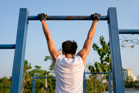 fitness ,sport, exercise, training and lifestyle concept - one youngman doing pull ups on horizontal...