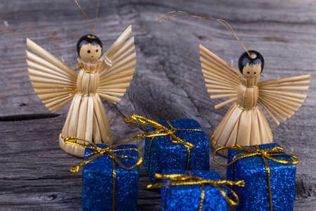 Two angels of straw and Christmas Package on wooden background
