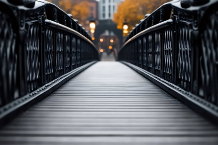 Wooden planks create leading lines on bridge with black metal railings leading towards blurred city backgroundの素材