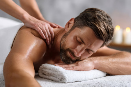 Man with beard enjoying a calm massage treatment in a spa with closed eyesの素材