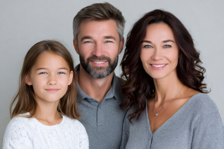 Family of three smiling, posing for a studio shot on a light backgroundの素材