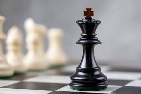 Black king chess piece leading the game with leadership and strategy against white piecesの素材