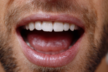 Man with beard opening mouth, showing clean, straight, and strong teethの素材