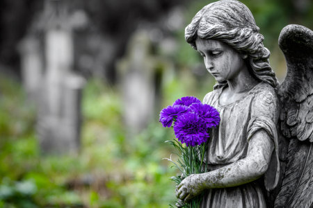 Angel statue holding bright purple flowers, symbolizing grief and remembranceの素材