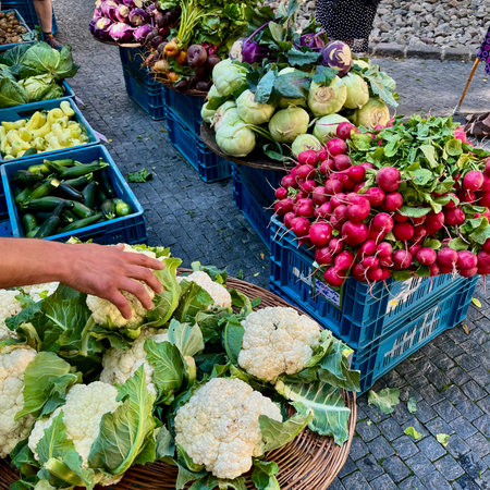 A mans hand picks up cauliflower at a farmers market in Prague. Naplavka market