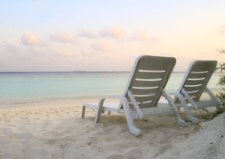 Pair of sunbeds beside tropical seaの写真素材