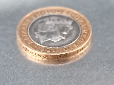 Two pounds coin lying down on silver plateの写真素材