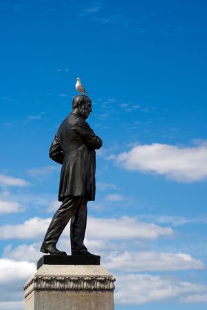 A seagull sits on the head of a bronze statue.の写真素材
