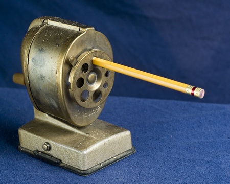 A dirty, antique style pencil sharpener with pencil inserted.の写真素材