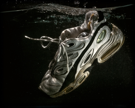A well worn and old tennis shoe floats submerged in water.の写真素材