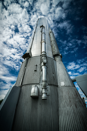 Looking up from the base of an historical, tall, steel Atlas Rocket reaching into a deep blue sky 