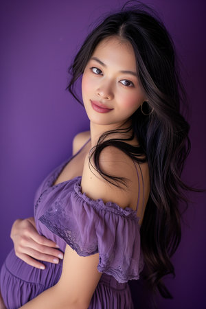 Portrait of a beautiful Asian woman in purple dress on purple backgroundの素材